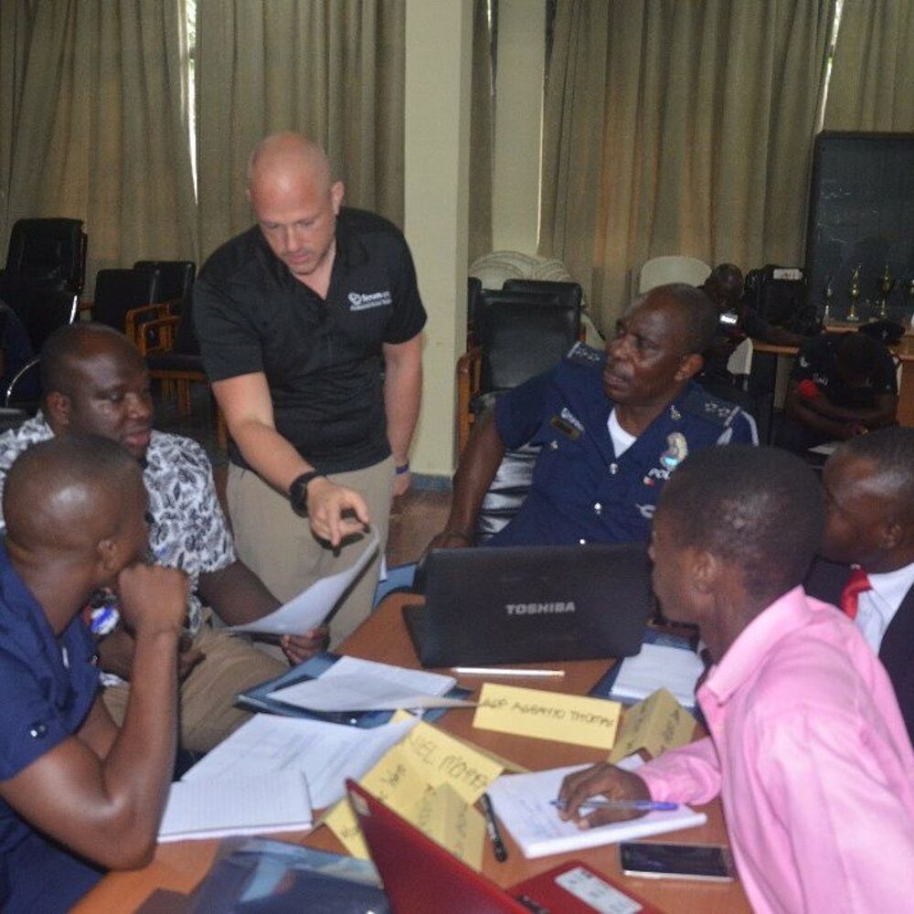 Martin Hinshelwood coaching a group of learners around a table during a training class